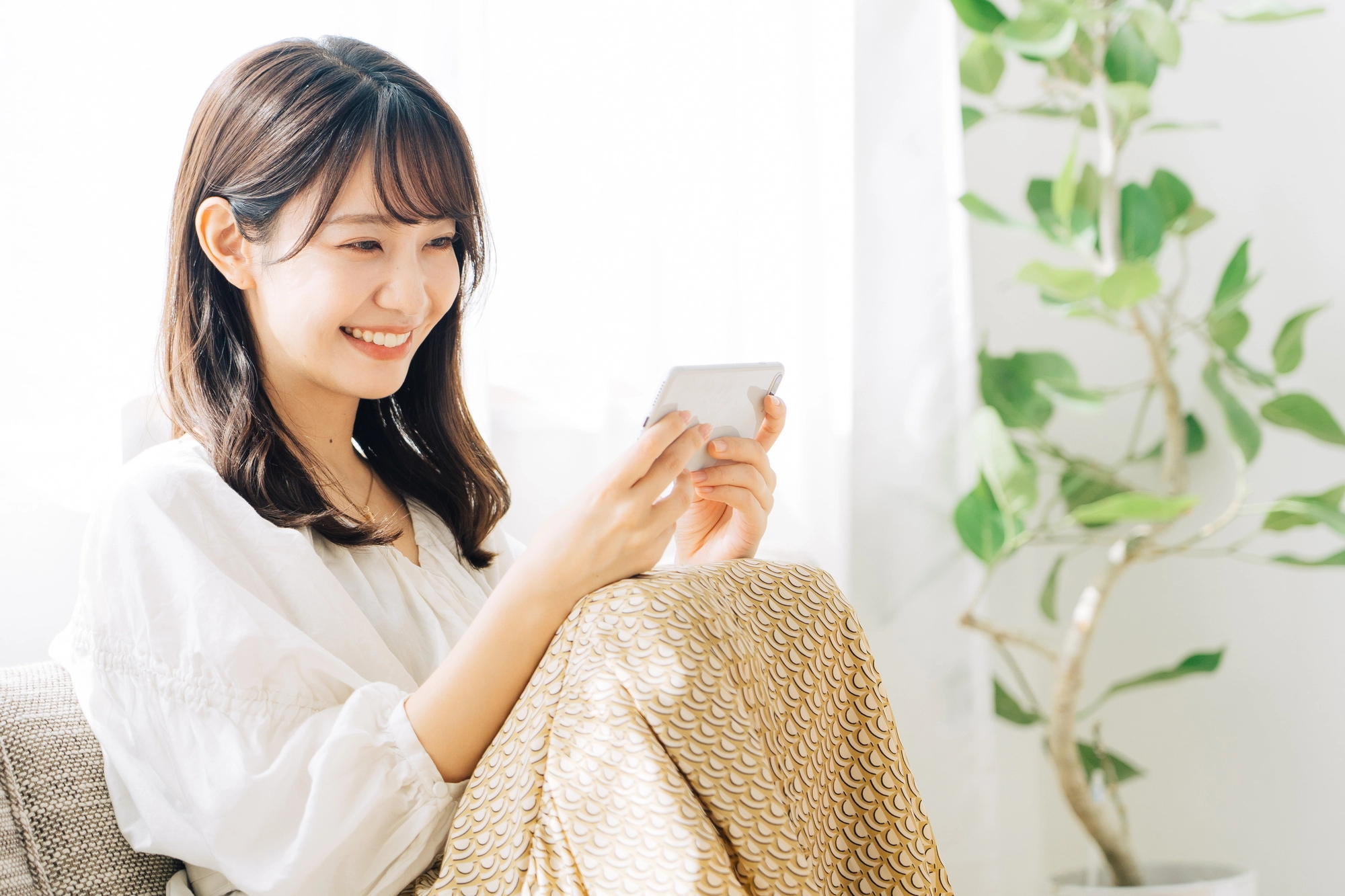 スマホをみて笑う女性のイメージ